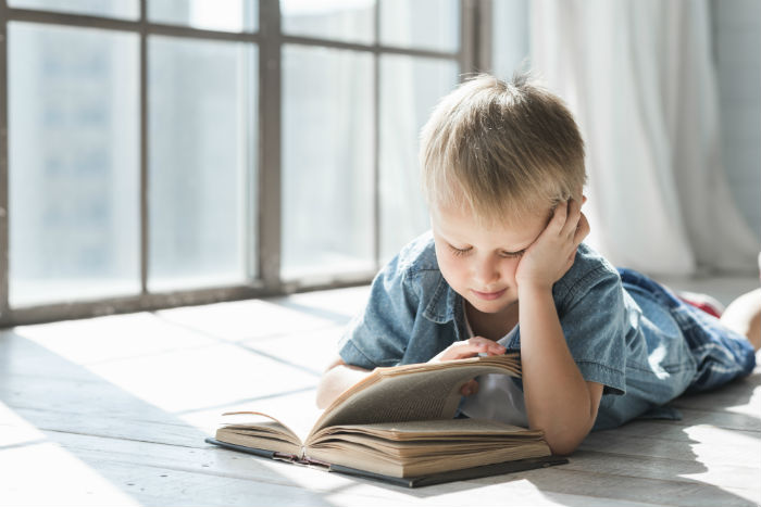 Menino lendo livro - Qual A Importância E Os Benefícios Da Leitura Na Infância